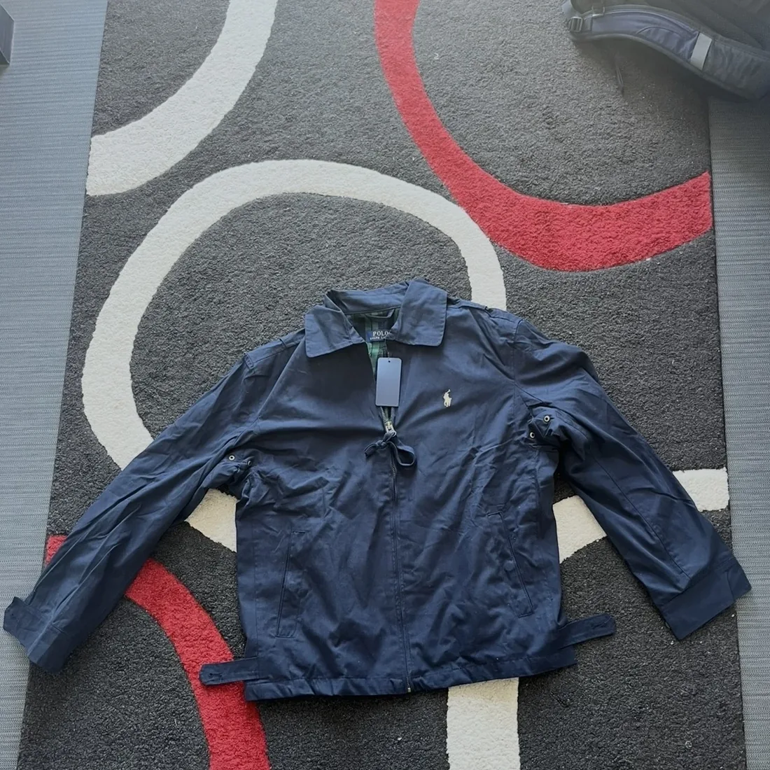 Photo brute d’une veste, posée sur un tapis
